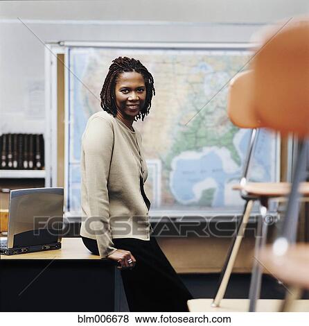 African American teacher sitting on desk in classroom View Large Photo Image Stock Photo - African American teacher sitting on desk in classroom. Fotosearch