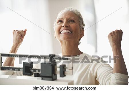 Picture - African American woman celebrating on scale. Fotosearch