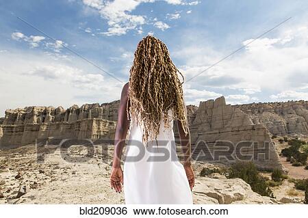 Stock Photograph - African American woman examining rock formations, Santa Fe, New Mexico, United States. Fotosearch