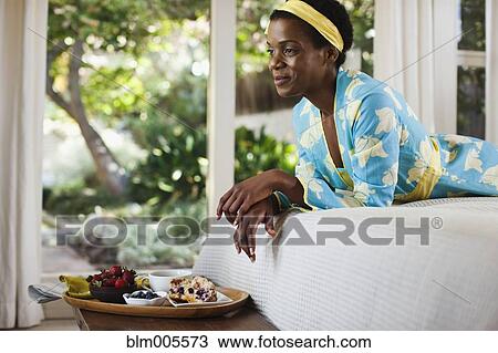 Stock Image - African American woman laying on bed. Fotosearch