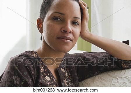 Stock Photo - African American woman on sofa. Fotosearch
