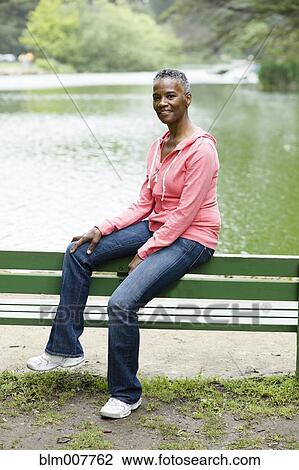 African American woman sitting on park bench near lake View Large Photo Image Stock Image - African American woman sitting on park bench near lake. Fotosearch