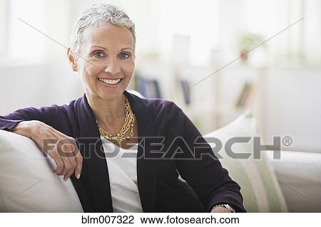 Stock Image - African American woman sitting on sofa. Fotosearch