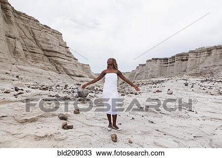 Stock Image - African American woman standing in rock formations, Santa Fe, New Mexico, United States. Fotosearch