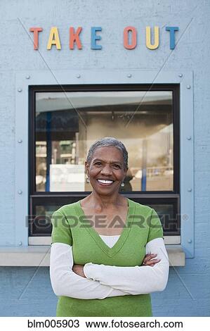 Stock Image - African American woman standing next to take out window. Fotosearch