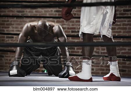 Stock Photo - African boxer kneeling on boxing ring mat. Fotosearch