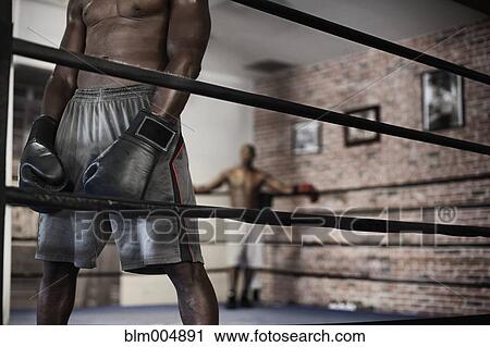 Stock Image - African boxer standing in boxing ring. Fotosearch