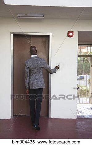 Stock Photography - African businessman pushing elevator button. Fotosearch