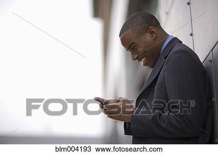 Stock Image - African businessman using cell phone. Fotosearch
