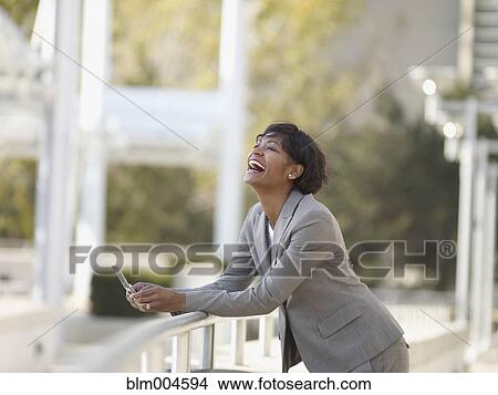 Picture - African businesswoman laughing and holding cell phone. Fotosearch
