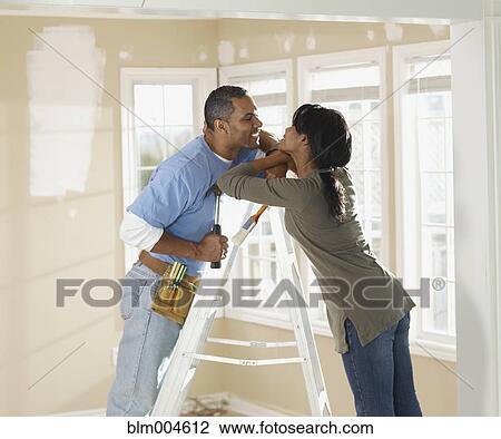 Stock Image - African couple decorating home together. Fotosearch