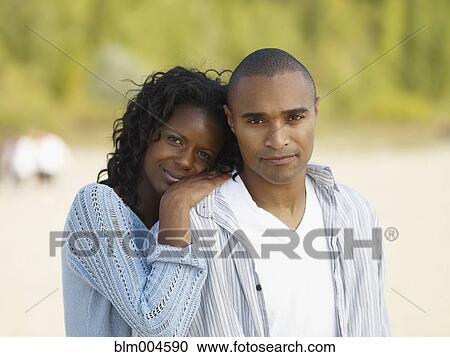 Stock Image - African couple hugging at beach. Fotosearch