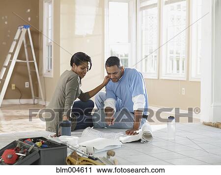Stock Image - African couple looking at blueprints. Fotosearch