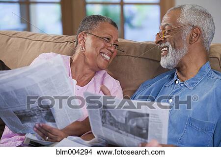 African couple reading newspaper on sofa View Large Photo Image Picture - African couple reading newspaper on sofa. Fotosearch
