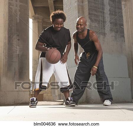 Stock Photograph - African father playing basketball with son. Fotosearch