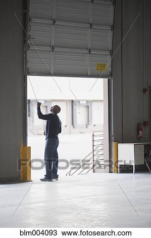 Stock Image - African man closing door in warehouse. Fotosearch