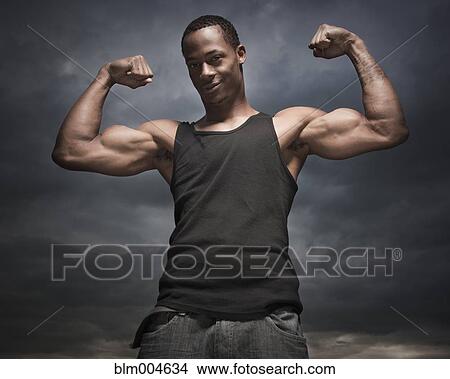 African man flexing arms, storm clouds in distance View Large Photo Image Picture - African man flexing arms, storm clouds in distance. Fotosearch