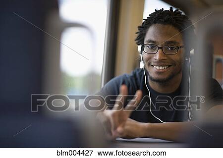 Stock Photo - African man listening to headphones and gesturing peace sign. Fotosearch