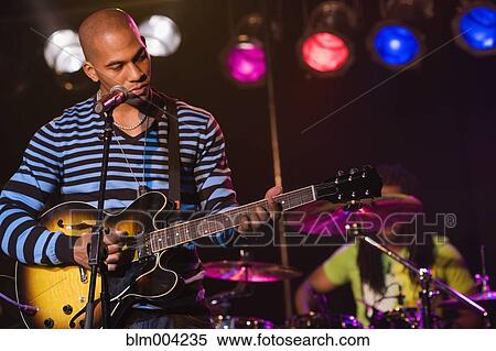 Stock Photography - African man playing electric guitar onstage. Fotosearch
