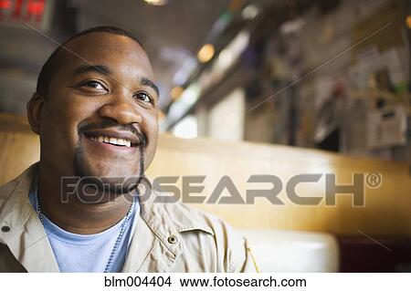 Picture - African man smiling in diner. Fotosearch
