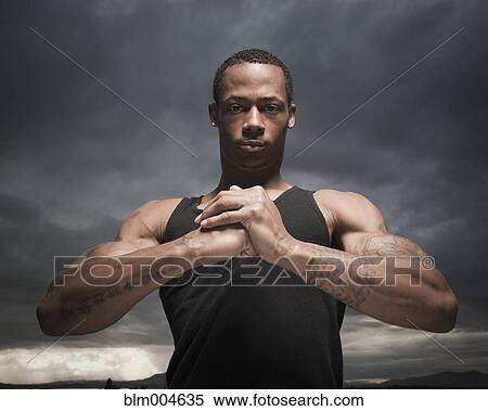Stock Photography - African man with hands clasped, storm clouds in distance. Fotosearch
