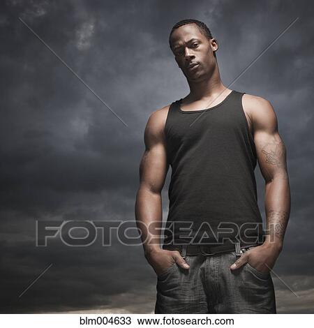 Stock Image - African man with hands in pockets, storm clouds in distance. Fotosearch