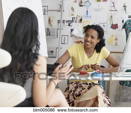 Stock Photograph - African seamstress talking to co-worker. Fotosearch
