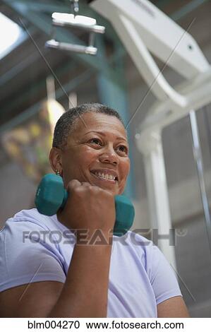Stock Image - African woman exercising with hand weight. Fotosearch