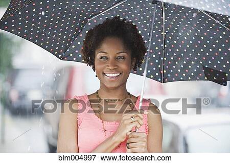 Stock Photo - African woman holding umbrella in rain. Fotosearch