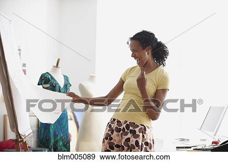 Stock Photo - African woman laughing at sketch in design studio. Fotosearch