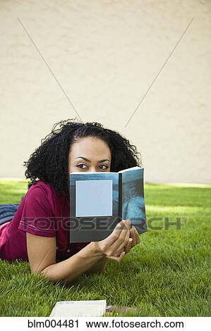 African woman laying in grass reading book View Large Photo Image Stock Image - African woman laying in grass reading book. Fotosearch