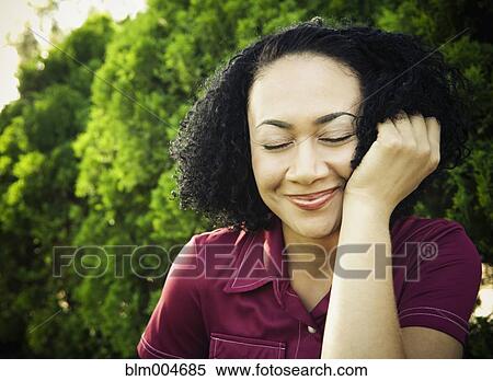 Stock Photography - African woman outdoors with eyes closed. Fotosearch