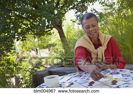 Stock Photo - African woman playing cards in garden. Fotosearch