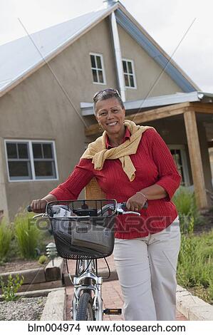 Picture - African woman pushing bicycle. Fotosearch