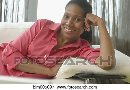Stock Photo - African woman relaxing on sofa. Fotosearch