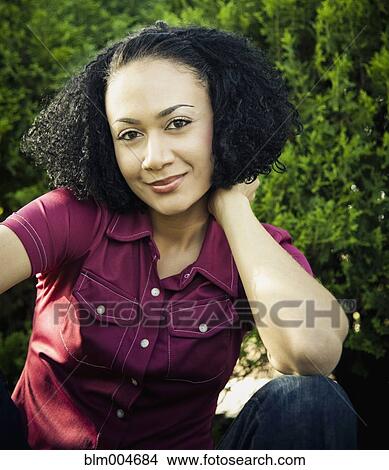 Picture - African woman sitting outdoors. Fotosearch