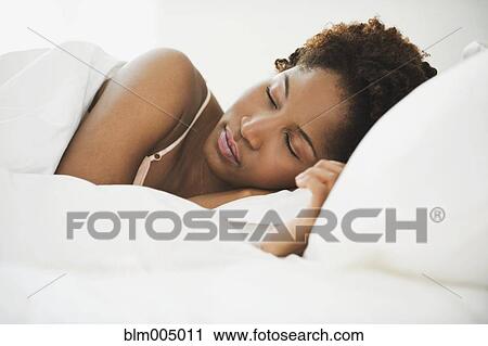 Stock Image - African woman sleeping in bed. Fotosearch