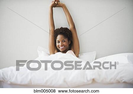 Stock Photo - African woman stretching in bed. Fotosearch