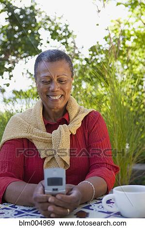 Stock Photo - African woman text messaging on cell phone. Fotosearch