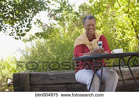 Stock Photography - African woman text messaging on cell phone. Fotosearch