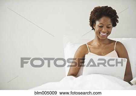 African woman using laptop in bed View Large Photo Image Stock Photo - African woman using laptop in bed. Fotosearch