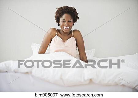 Stock Photo - African woman waking up on bed. Fotosearch
