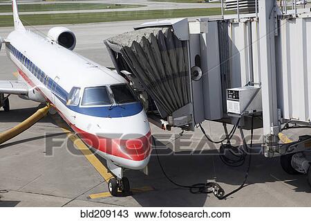 Stock Image - Airplane and passenger boarding bridge on runway. Fotosearch
