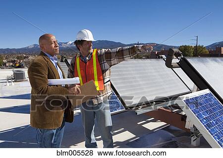 Architect and construction worker on rooftop near solar panels View Large Photo Image Stock Photo - Architect and construction worker on rooftop near solar panels. Fotosearch