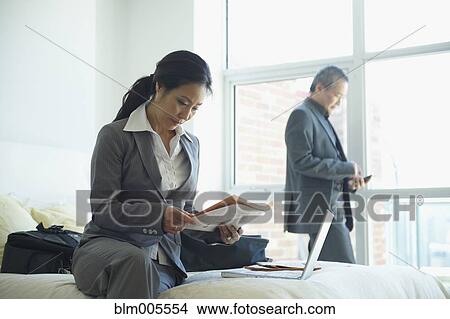 Picture - Asian businessman and businesswoman working in hotel room. Fotosearch