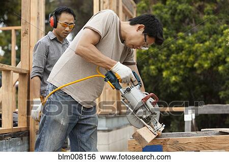 Asian construction worker using saw to cut lumber View Large Photo Image Stock Photograph - Asian construction worker using saw to cut lumber. Fotosearch