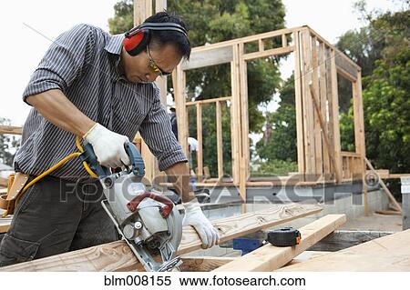 Asian construction worker using saw to cut lumber View Large Photo Image Stock Photography - Asian construction worker using saw to cut lumber. Fotosearch
