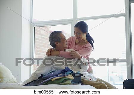 Stock Image - Asian couple hugging in bedroom. Fotosearch