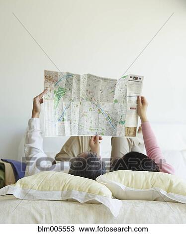 Stock Image - Asian couple looking at map in bedroom. Fotosearch
