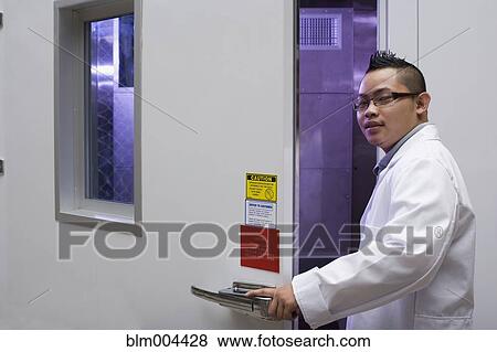 Asian man in lab coat opening door View Large Photo Image Stock Photo - Asian man in lab coat opening door. Fotosearch